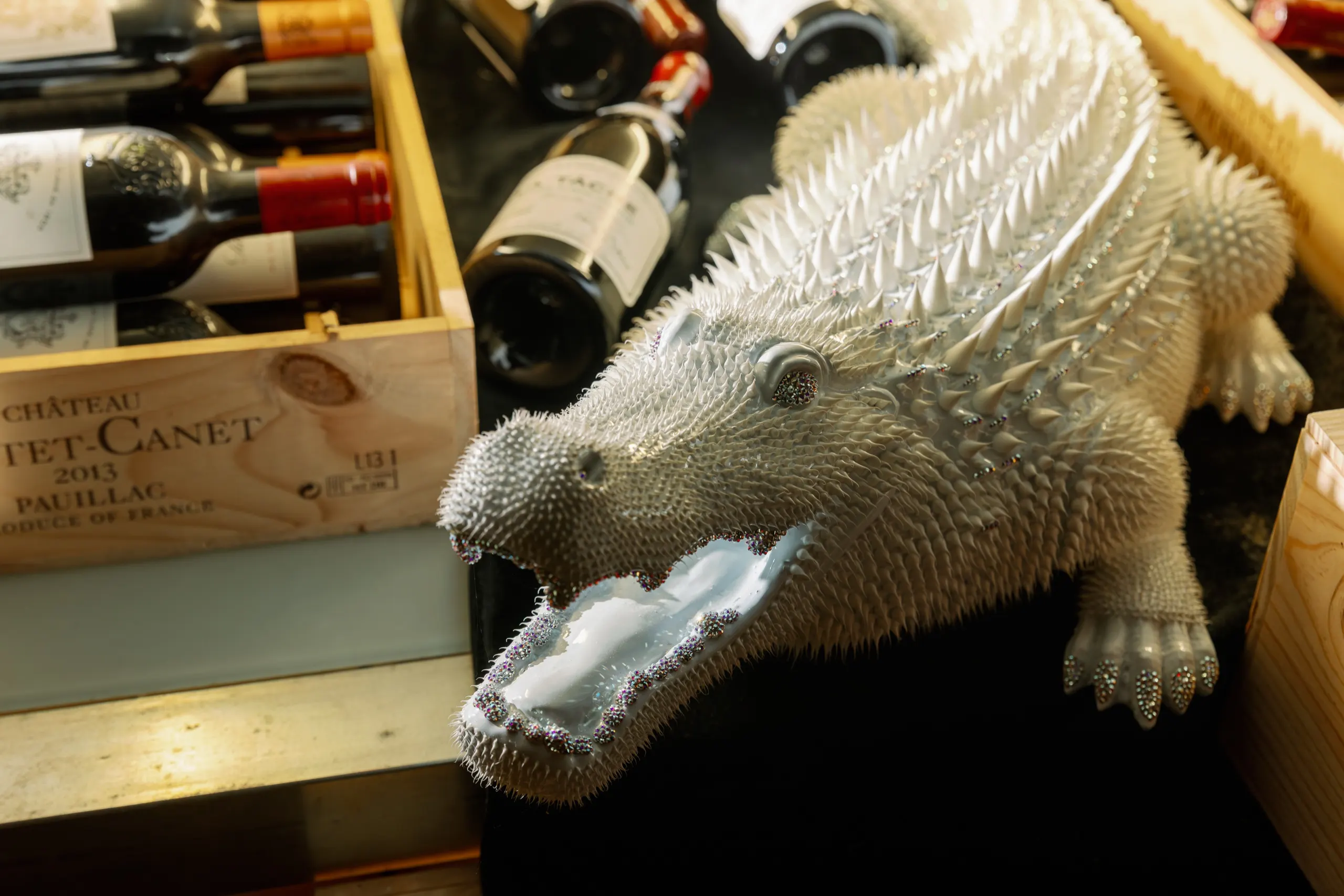 Scultura di coccodrillo in cristallo tra le casse di vino