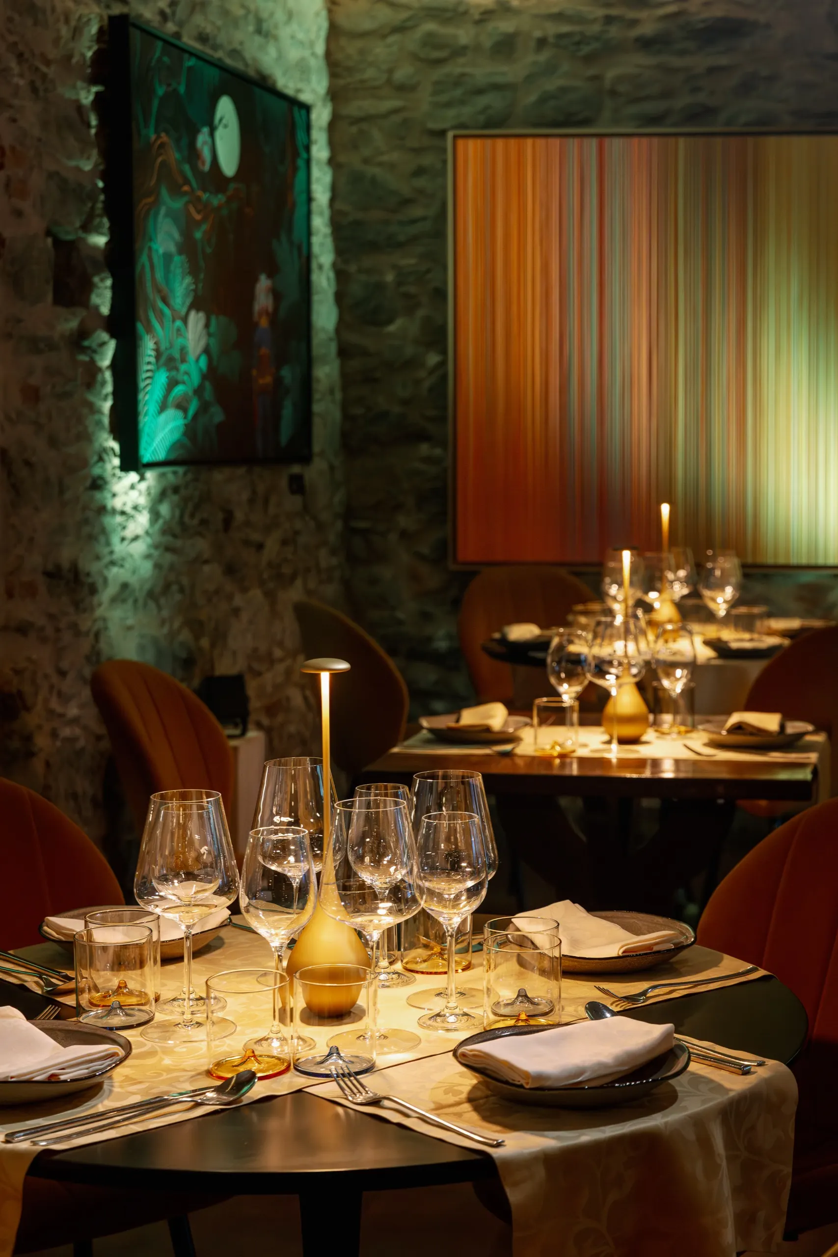 Sala da pranzo in pietra con opere d’arte illuminate alle pareti